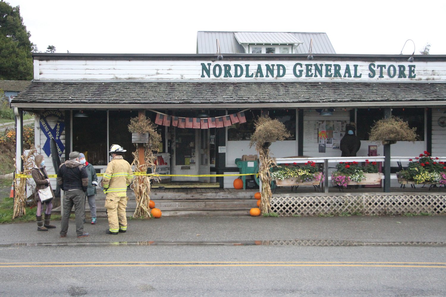 Nordland residents chat with a firefighter following an early morning fire at the Nordland General Store.